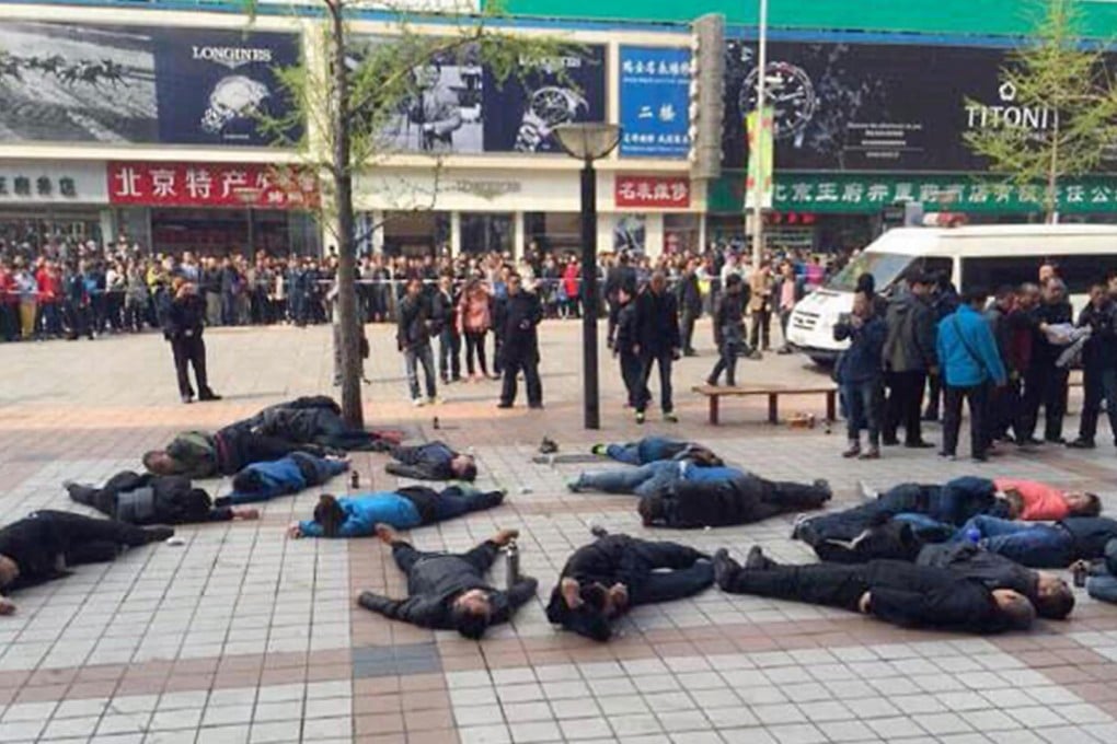 The taxi drivers lie unconscious outside the shopping mall in Wangfujing. Police said they were out of danger. Photo: SMP Pictures
