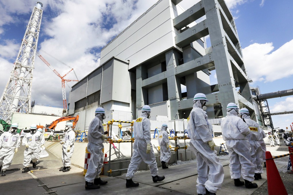 Tokyo Electric Power Co's workers and foreign journalists walk past reactor building of Unit Four at tsunami-crippled Fukushima Daiichi Nuclear Power Plant. Photo: EPA