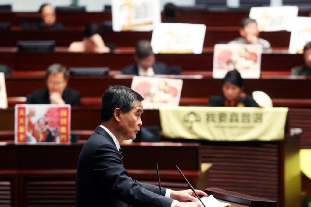 Chief Executive Leung Chun-ying attends a question & answer session on his policy address, while pro-democracy lawmakers hold yellow banners saying "I want genuine universal suffrage" at the back on January 15, 2015. Photo: Sam Tsang
