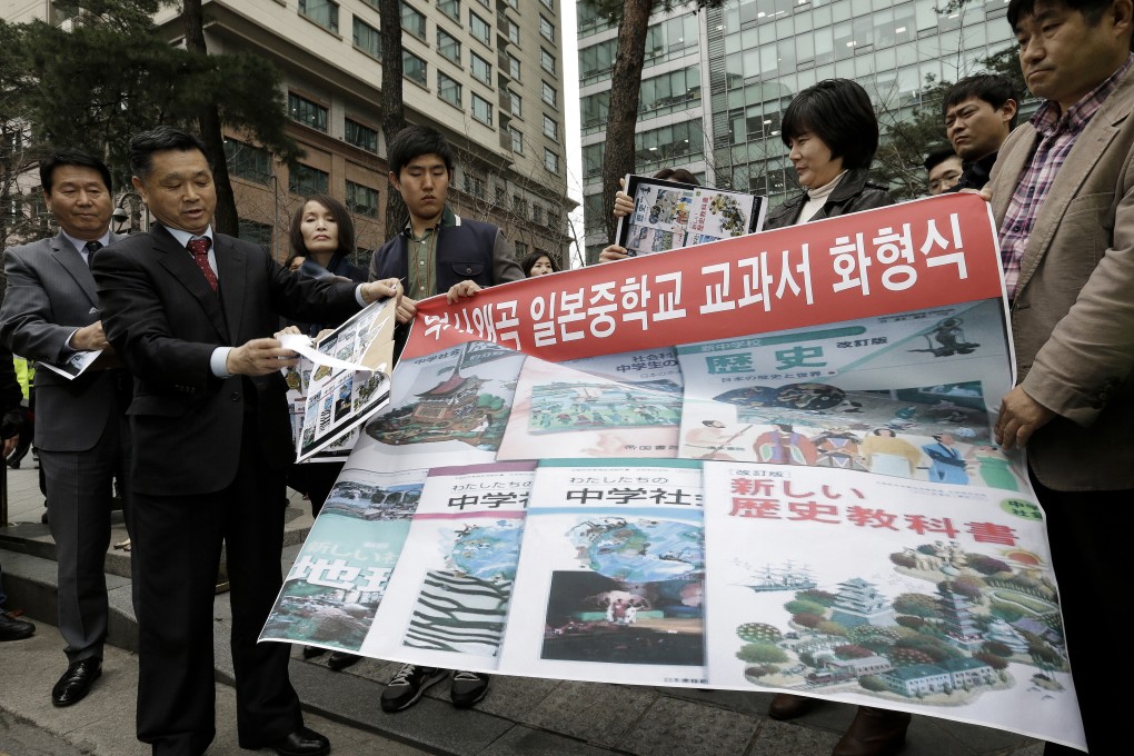 A South Korean protester tears off a copied paper which has images of covers of Japan's new school books for social studies and history during a rally against Japan in front of the Japanese Embassy in Seoul. Photo: AP