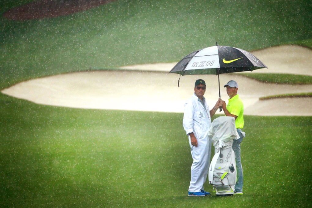 Rory McIlroy and his caddie practise in the rain. Photo: AFP