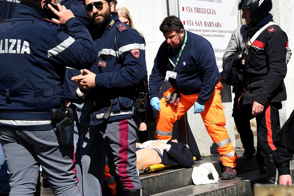 Rescuers and police help an injured man out of the Milan court. Photo: EPA