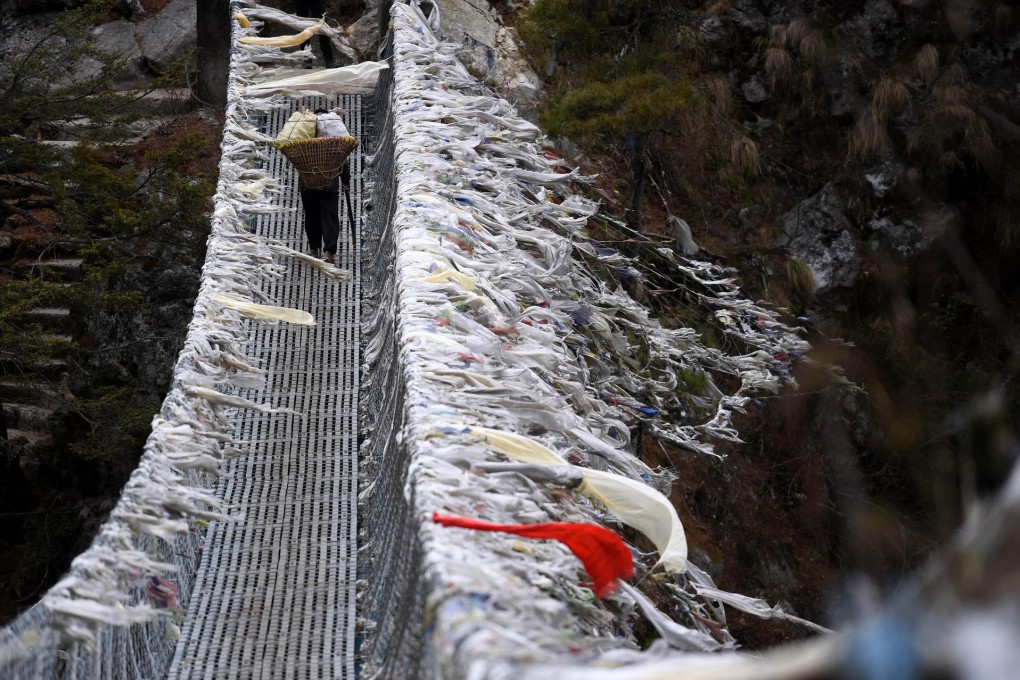 A Nepali porter walks on a suspension bridge over a deep valley near Labja Dorhan on his way to the town of Namche Bazar.Photo: AFP