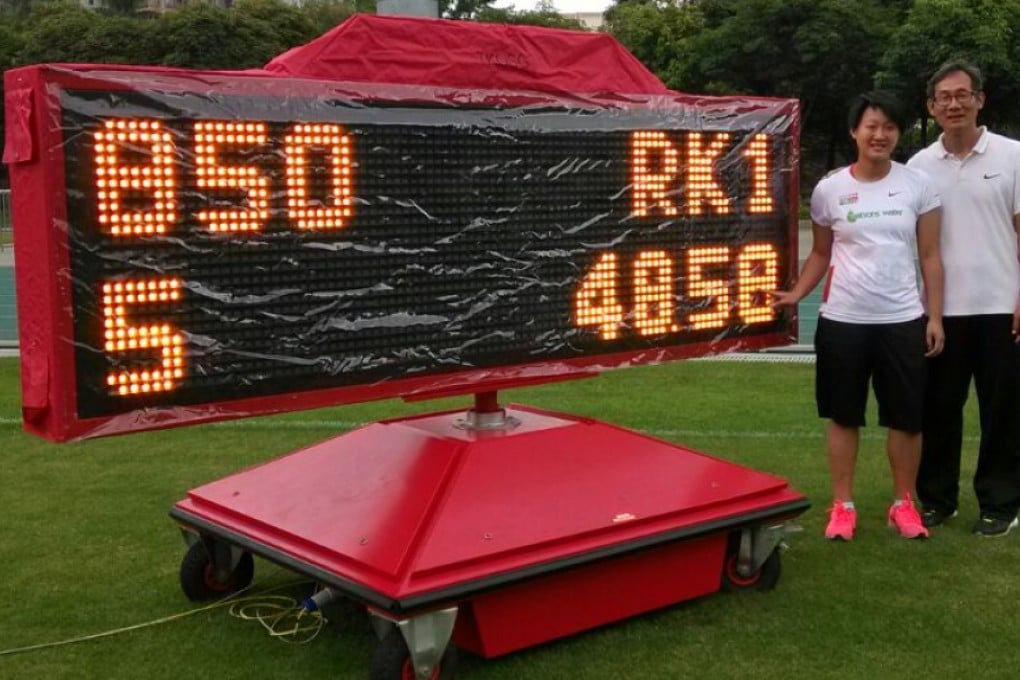 Woo Wing-tung poses beside her new record mark of 48.58 metres for the women's javelin. Photos: SCMP Pictures