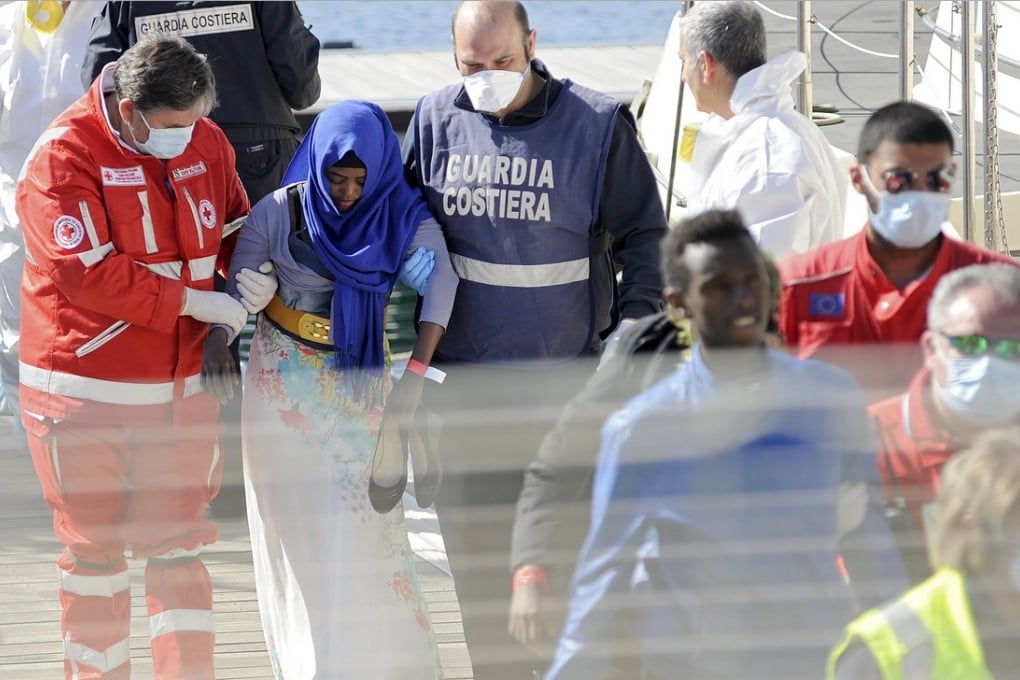A migrant is helped as she disembarks from a Coast Guard boat in the Sicilian harbour of Palermo. Photo: Reuters
