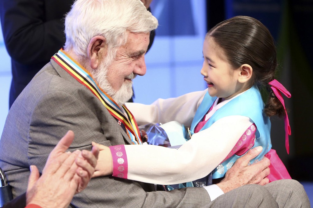 Korean War hero Bill Speakman, 87, is greeted by a young South Korean girl during the presentation ceremony for his medals. Speakman said the medal originated in South Korea, so it should be returned there. Photo: Lee Dong-geun