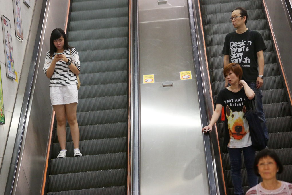 A woman looks at her phone on an escalator inside a Hong Kong MTR station. The mobile video market in the city is heating up. Photo: David Wong