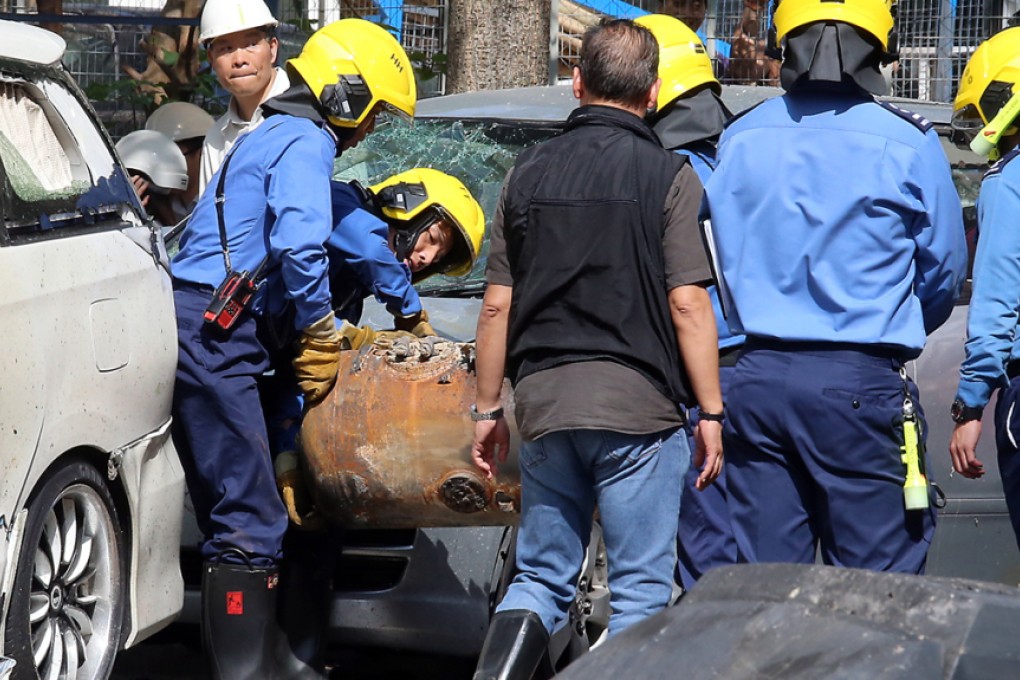 Firemen move a exploded gas tank as the investigation and clearing continue at the garage in Wong Tai Sin after an explosion on Sunday. Photo: David Wong