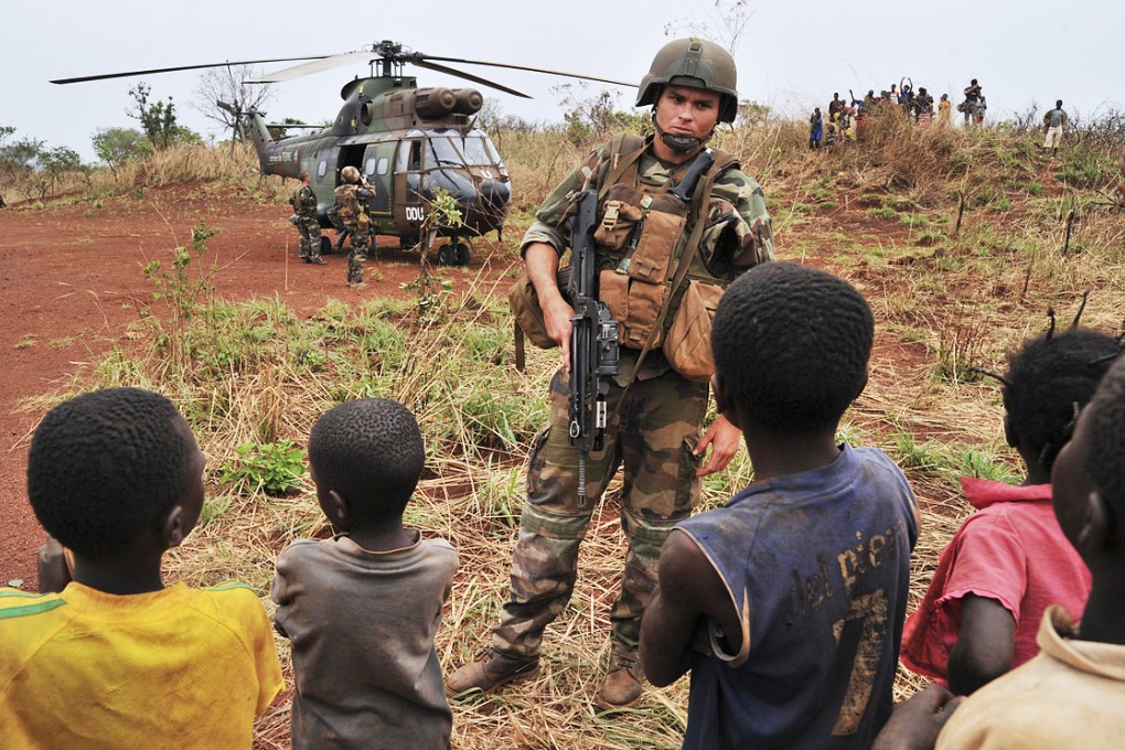 A French soldier stands guard in front of a helicopter transporting officers in the Central African Republic during a peackeeping operation in February 2014. Photo: AFP