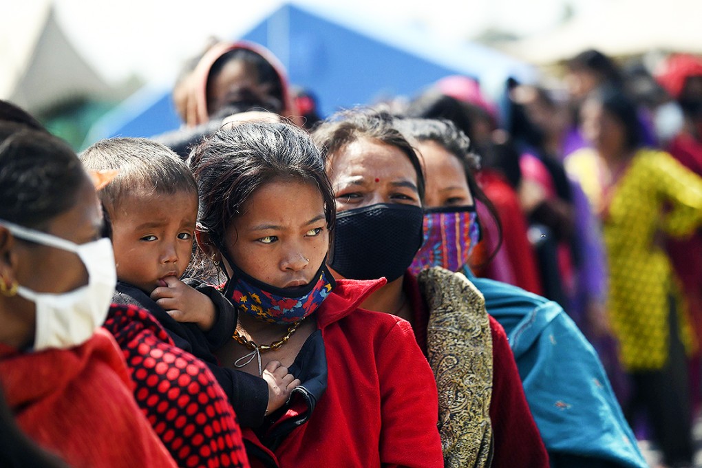 A Nepalese woman and her child line up with others to receive a daily stipend of food from the Nepalese army at a camp in Kathmandu. Photo: AFP