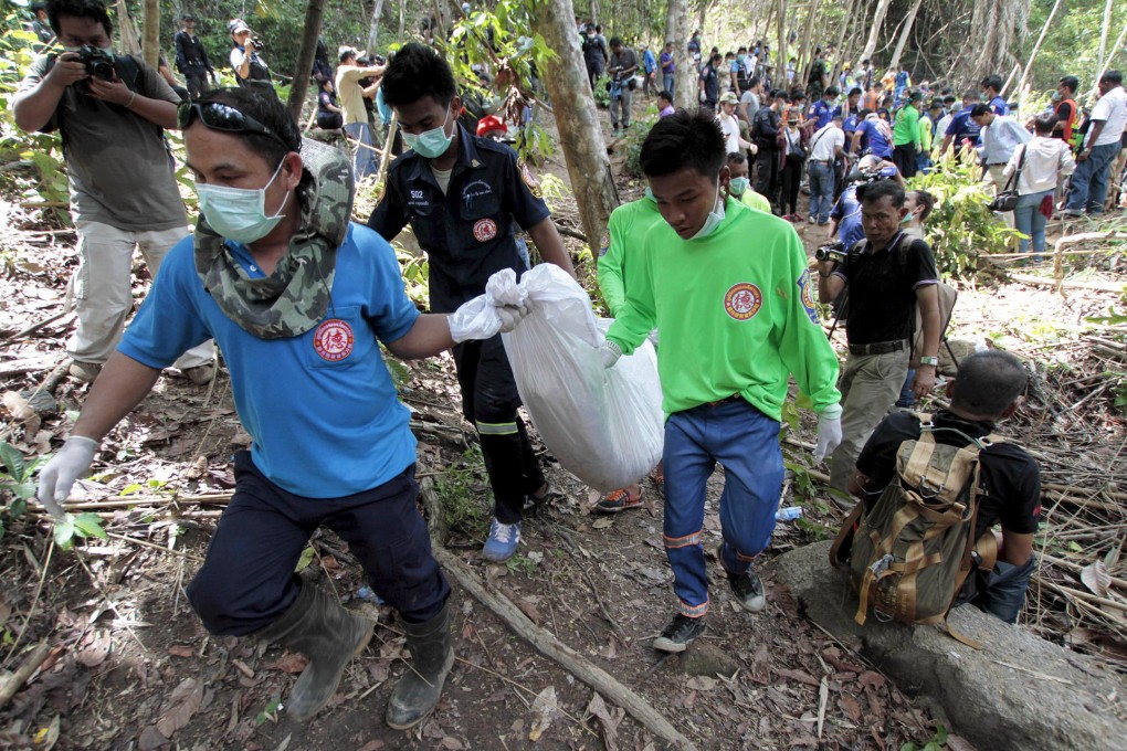 Workers carry a body bag with remains retrieved from a mass grave at an abandoned camp in Thailand's Songkhla province.Photo: Reuters