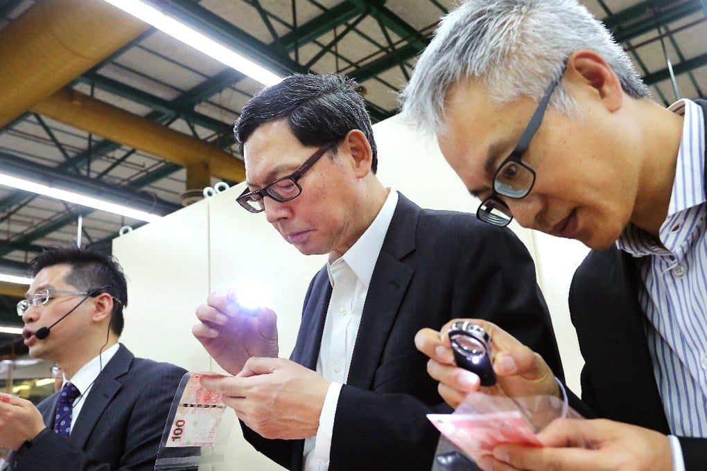 Monetary Authority chief Norman Chan (centre) and executive director monetary management Howard Lee inspect notes. Photo: SCMP