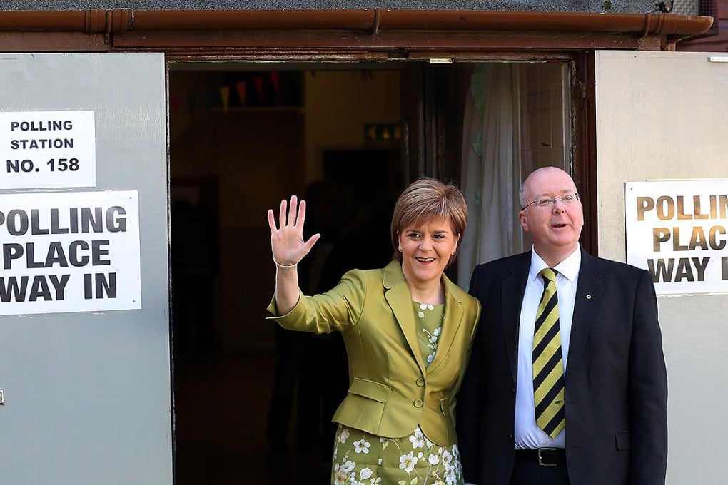 First Minister of Scotland and Scottish National Party leader Nicola Sturgeon and her husband Peter Murrell pose for photographs after casting her ballot at Broomhouse Community Hall. Photo: AP