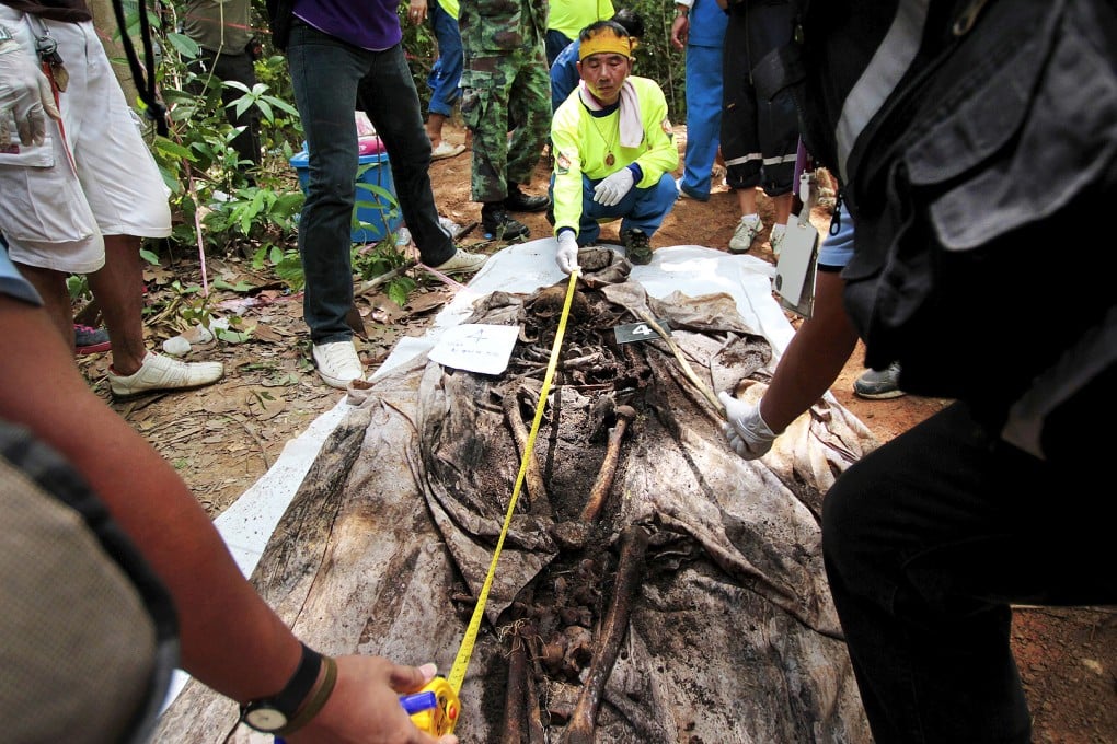 Rescue workers and forensic experts measure human remains retrieved from a mass grave at a rubber plantation near a mountain in Thailand's southern Songkhla province. Photo: Reuters