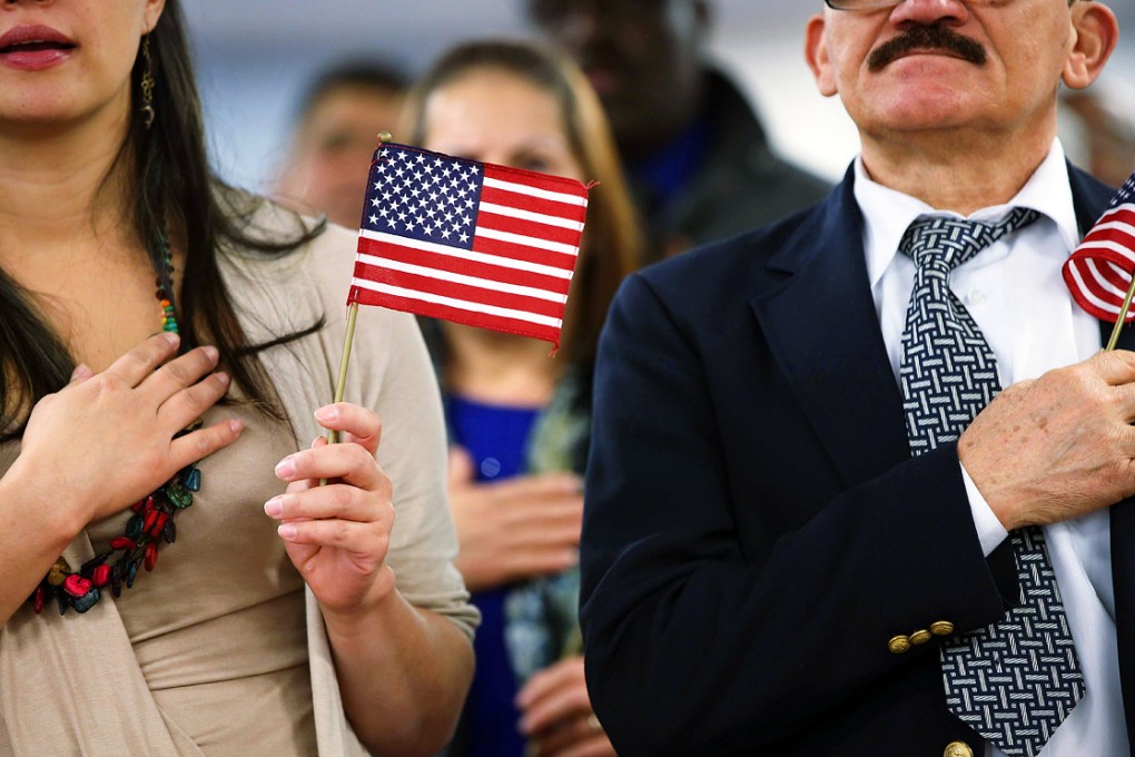 Immigrants hold American flags and listen to the national anthem during a naturalization ceremony at the district office of U.S. Citizenship and Immigration Services (USCIS) in Newark, New Jersey. Photo: AFP