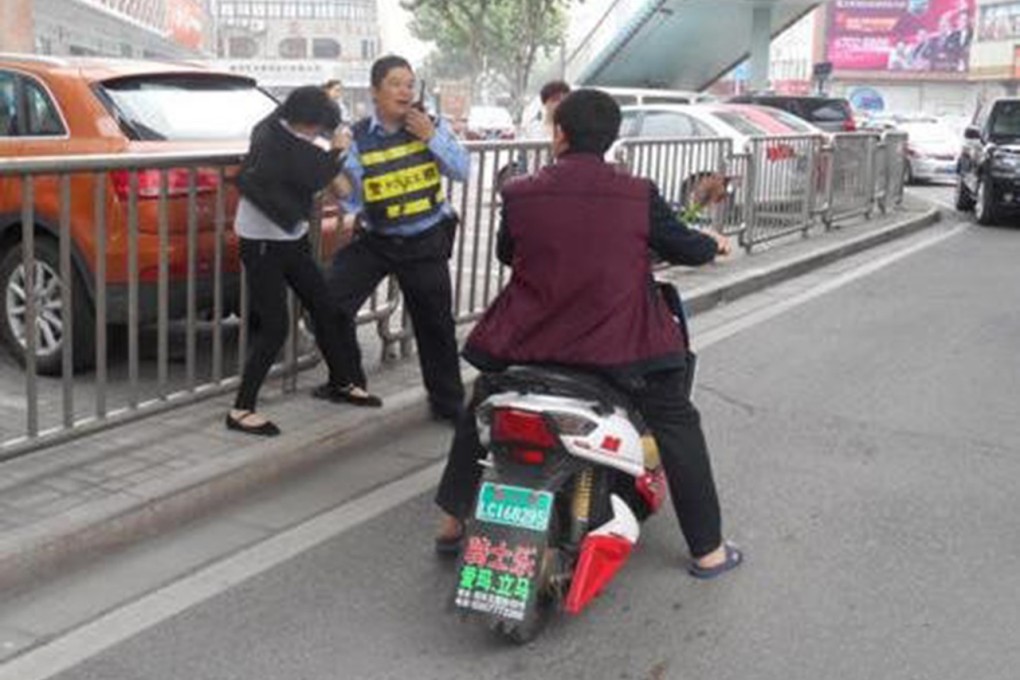 The police officer and woman passenger scuffle on a road in Shenyang. Photo: Weibo