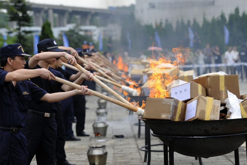 Customs official in Humen, Guangdong province, burn packages containing heroin seized following a crackdown there. Photo: Xinhua