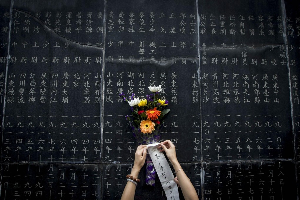 A visitor places flowers on the Nanking Massacre monument that lists victims' names. Photo: AFP