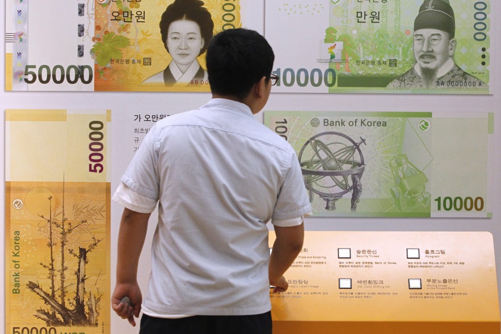 A student in Seoul looks at oversized Korean won bank notes after the Bank of Korea voted to keep rates steady at a record low for the second month running. Photo: Reuters