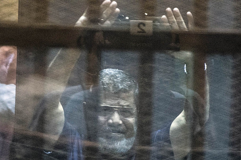 Mohammed Mursi raises his hands as the judge reads out the verdict sentencing the ousted president and more than 100 other defendants to death. Photo: AFP