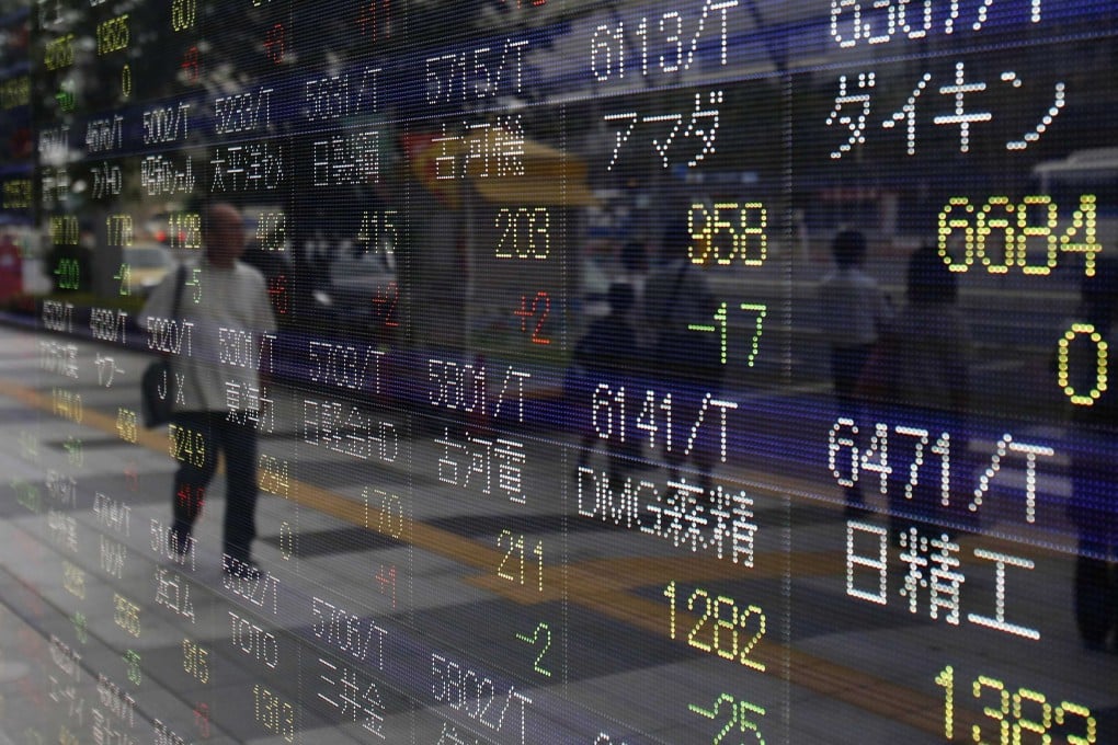 A pedestrian is framed at the different prices of financial markets in Japan as investors scramble for various issues in Asia. Photo: Reuters