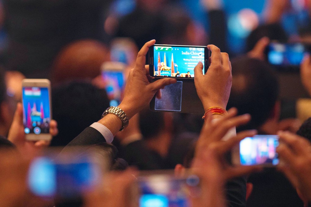 India's Prime Minister Narendra Modi is seen on mobile phone screens while he delivers a speech at the India-China Business Forum in Shanghai on May 16, 2015. Photo: AFP