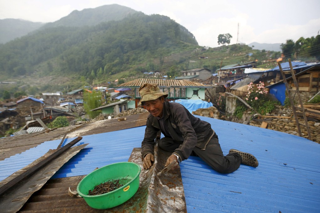 A man in Barpak village, in Nepal's Gorkha district, tries to repair the roof of his brother's house. Photo: Reuters