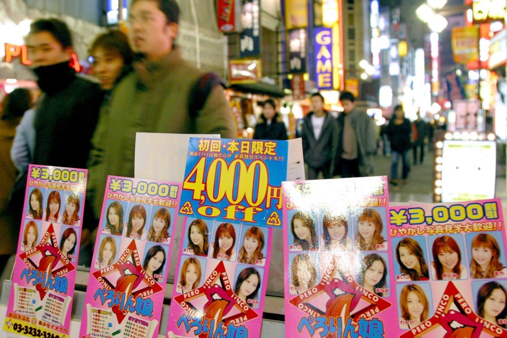 Men walk past an advertisement for a massage parlour in Tokyo's Kabukicho red-light district. Photo: Reuters