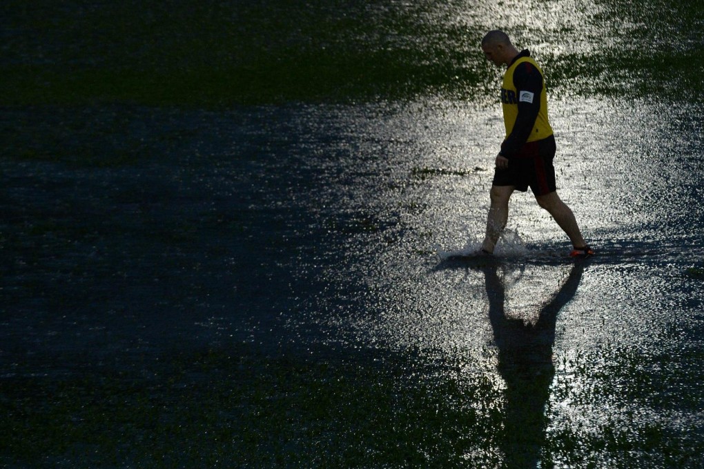 A trainer inspects the field during the Asia Rugby Championship clash between Hong Kong and Japan at Aberdeen. Officials eventually decided to abandon the match, which was halted after 13 minutes. Photo: AFP