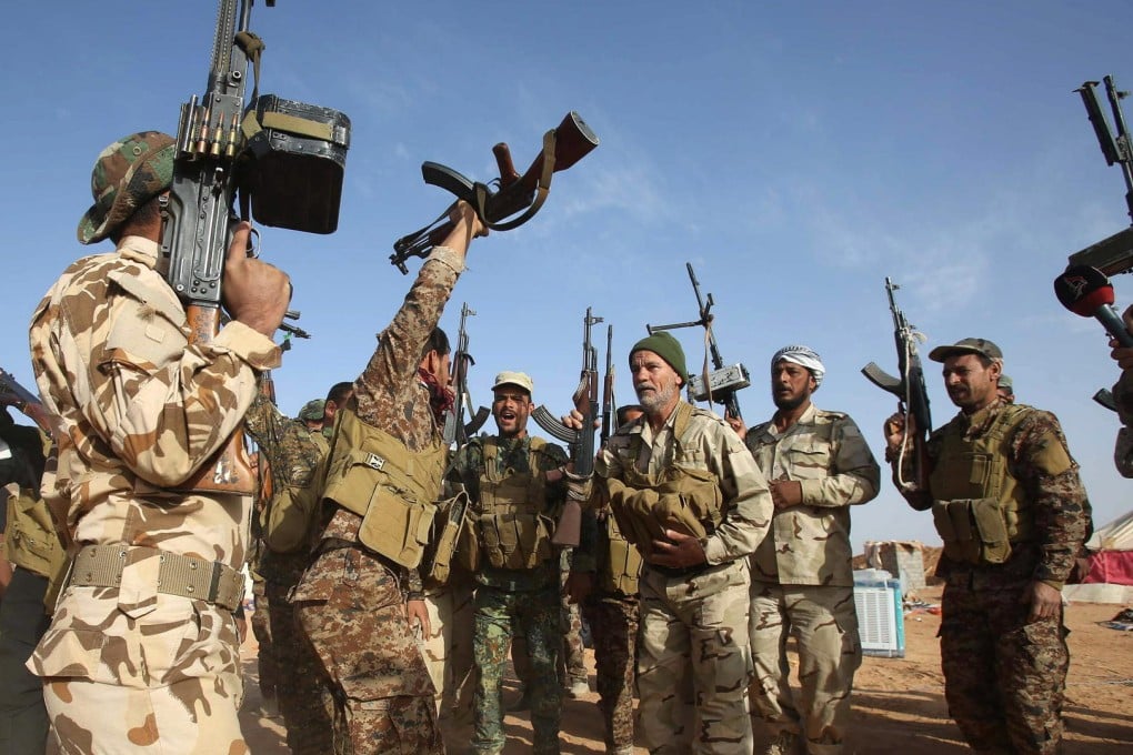Iraqi fighters from a Shiite militia group hold up their weapons in Nukhayb after hitting back against Islamic State. Photo: AFP