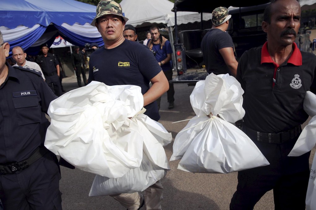 Policemen carry bags with human remains found at the site of trafficking camps. Photo: Reuters