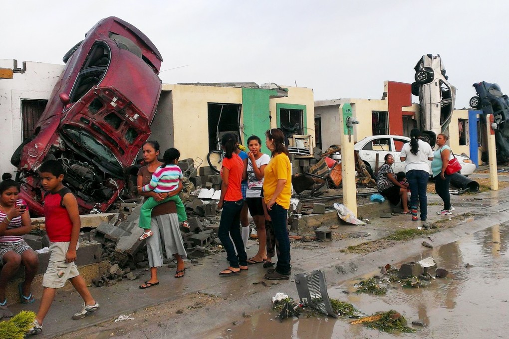 Residents survey the destruction wrought by a tornado that flung cars and razed homes in the Mexican town of Ciudad Acuna. Photo: Reuters
