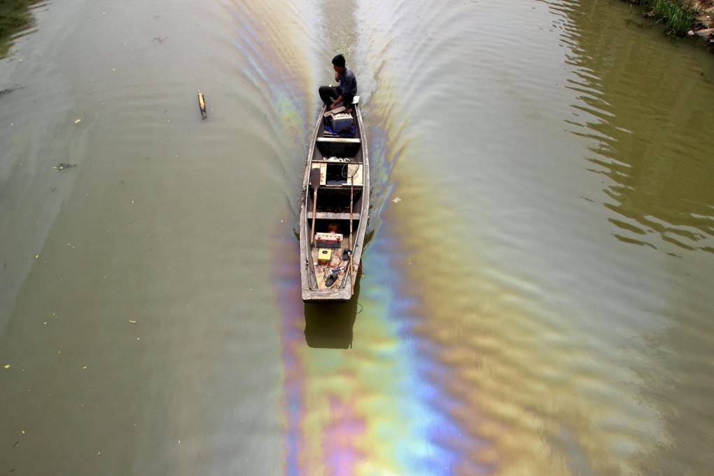 A man rides a boat in an oil-polluted river in Zhejiang.Photo: Reuters