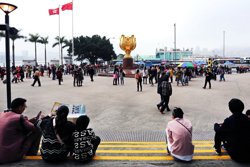 Tourists sit on the ground in Wan Chai's Golden Bauhinia Square in the absence of public seating. Photo: Felix Wong