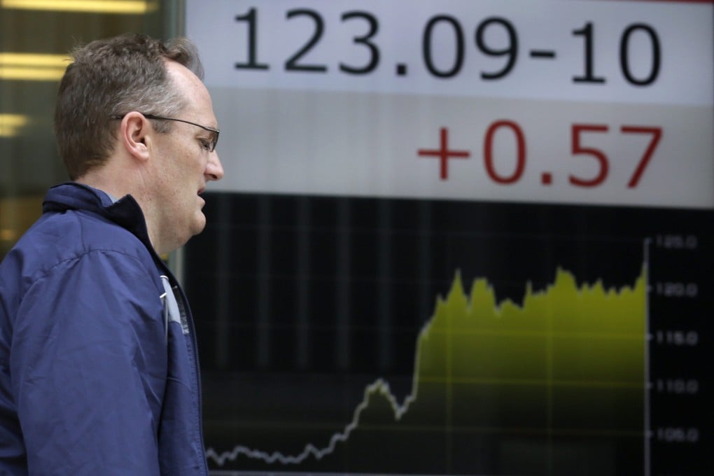 A tourist walks past a sign showing the exchange rate between the dollar and the Japanese yen as the greenback hit its highest level since 2002. Photo: EPA