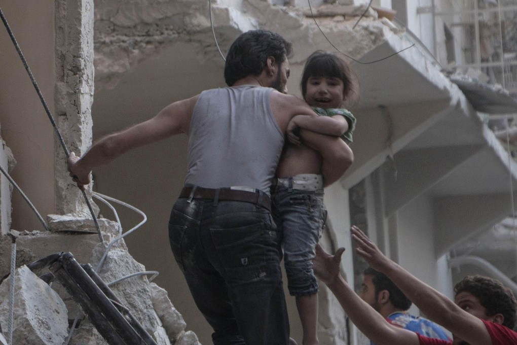 A man evacuates a child from a building in Aleppo.Photo: AFP