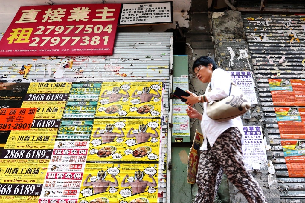 A woman walks past the poster-plastered front of a vacant shop in Causeway Bay, one of the city’s main shopping areas. Photo: David Wong
