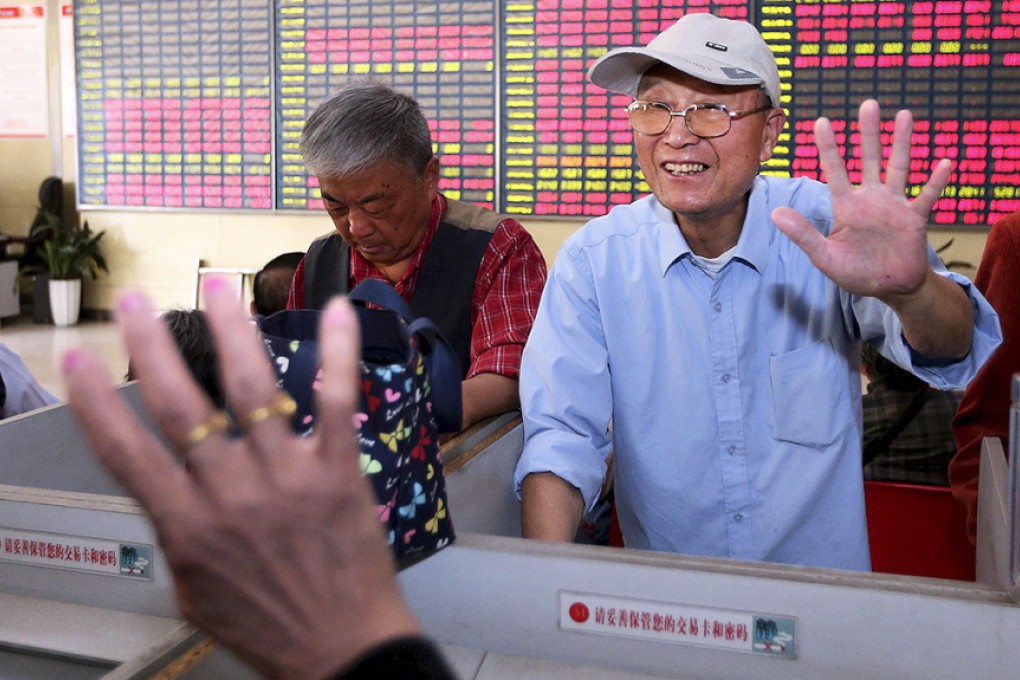 A man gestures "five" to another investor as the Shanghai Composite Index reached 5,000 points at a brokerage house in Nantong, Jiangsu province. Photo: Reuters