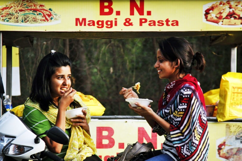 Indian girls eat noodles at a roadside stall in Ahmadabad, India. Photo: AP
