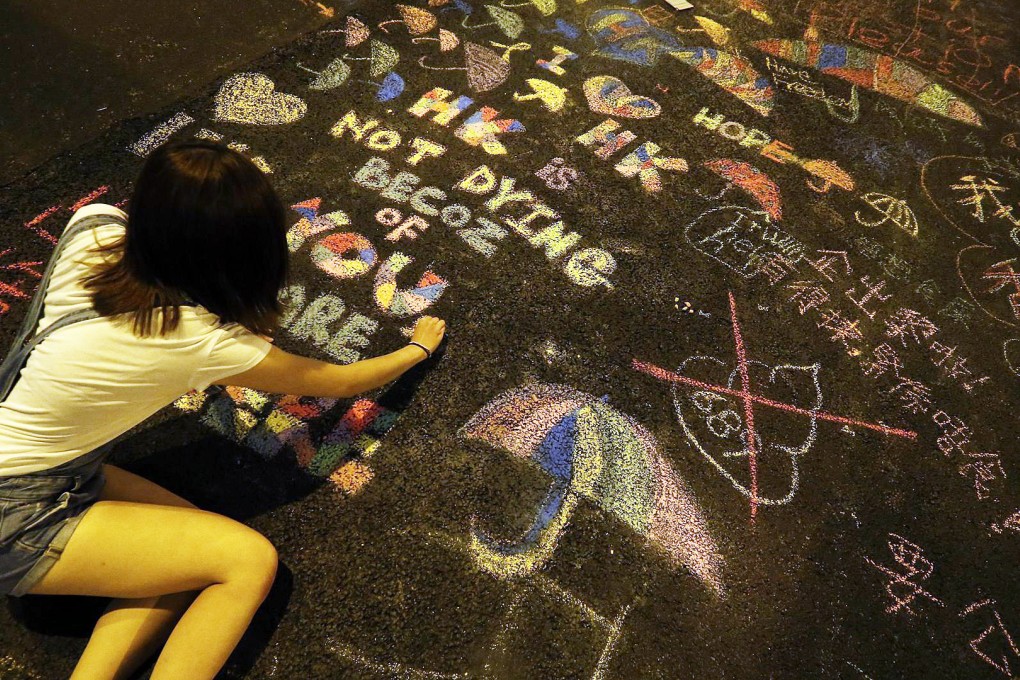 A protester writes a message on a road in Admiralty during the Occupy Central demonstrations last year. Photo: EPA