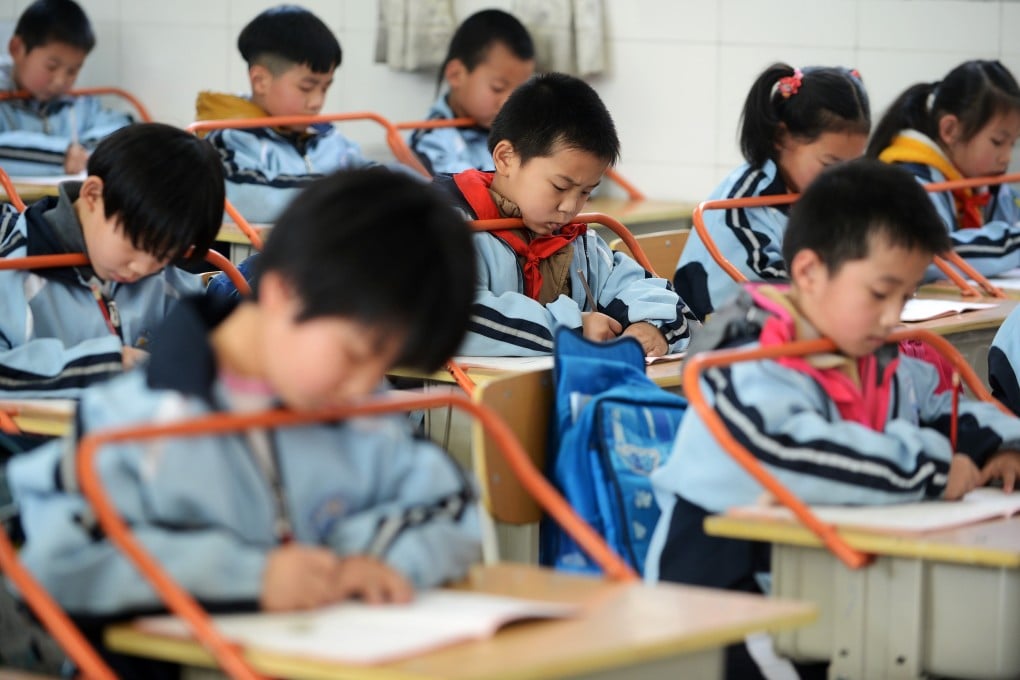 Pupils have their heads put on a myopia-prevention racks as they write in a classroom in Wuhan, Hubei Province. Photo: Xinhua