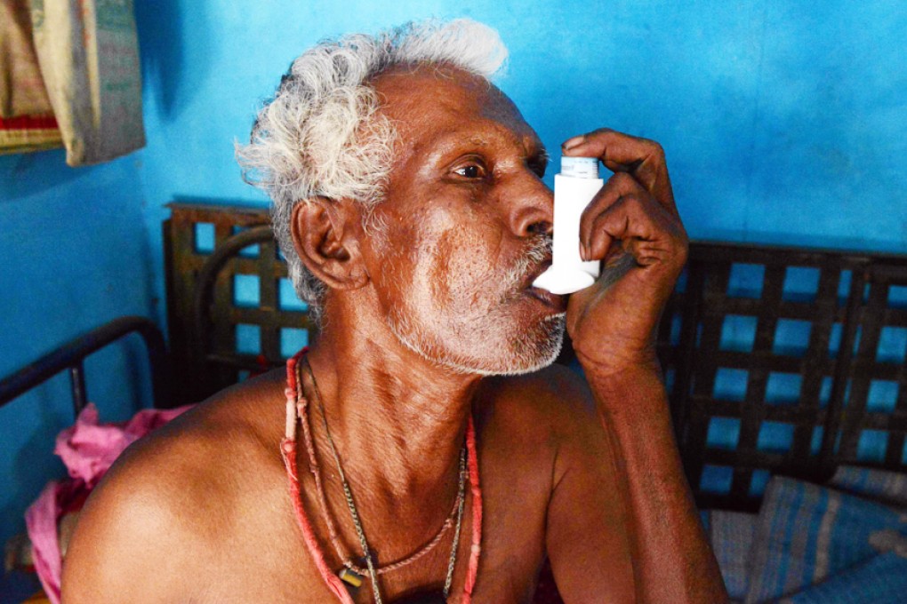 Sixty four year old Indian asbestosis sufferer Chinnapan Chinnakannu uses an inhaler at his residence in the village of Kaligam, on the outskirts of Ahmedabad. Photo: AFP