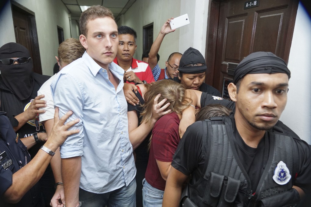 Dutch national Dylan Snel (left, in blue shirt) is escorted by police as he and three others leave the court in Kota Kinabalu. Photo: AP