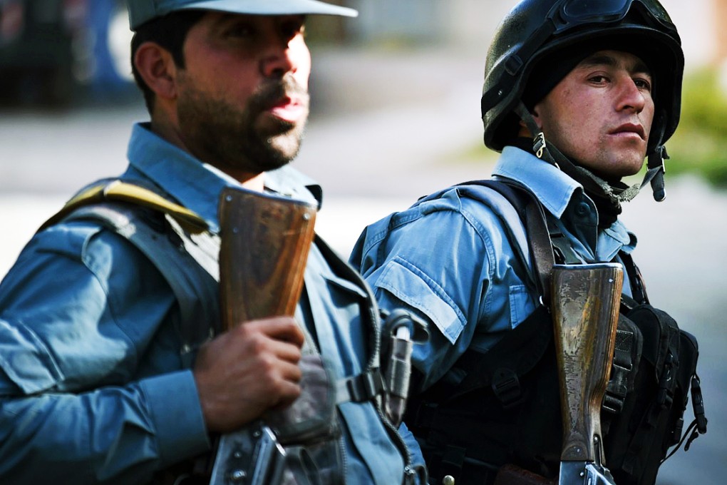 Two Afghan policemen keep watch near the gates of the Heetal Hotel in Kabul. Photo: AFP