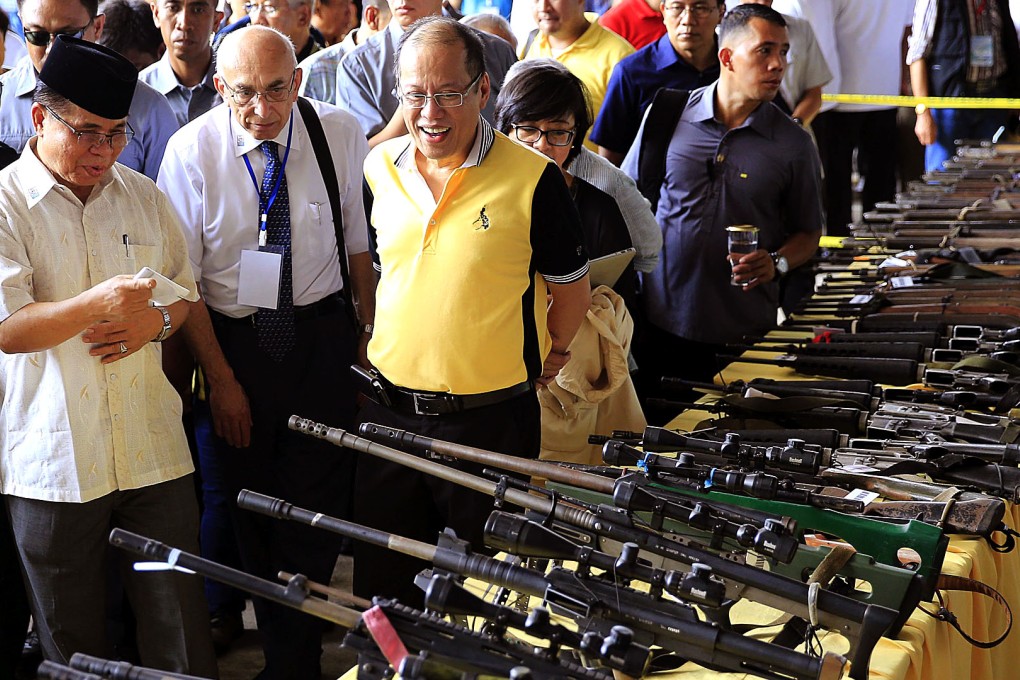 Philippine President Benigno Aquino III (2nd from left) and Al-haj Murad Ebrahim (left), chairman of the Moro Islamic Liberation Front (MILF), look at weapons turned over by the rebel group as part of a peace treaty. Photo: Reuters