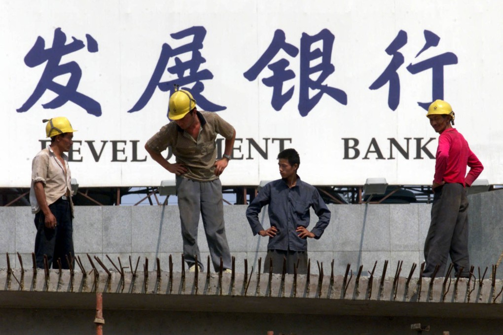 Workers stand in front of a sign of the Pudong Development Bank, which announced on Tuesday it will buy a 97.3 per cent of Shanghai Trust. Photo: Reuters