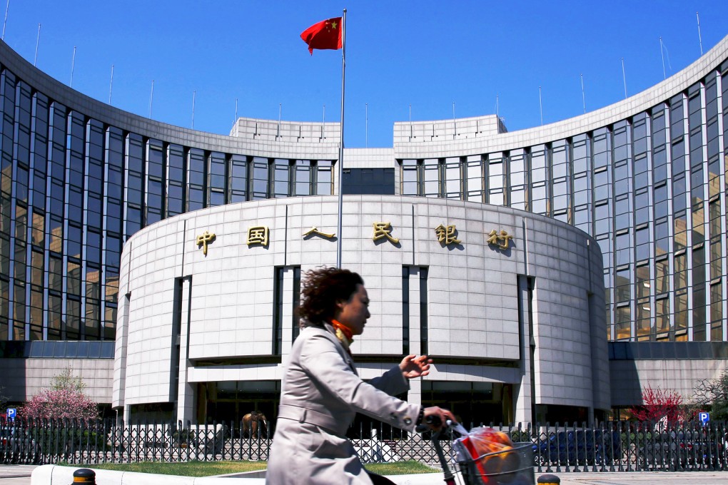 A woman rides past the headquarters of the People's Bank of China. The bank wants to find a way to lower the costs of borrowing. Photo: Reuters