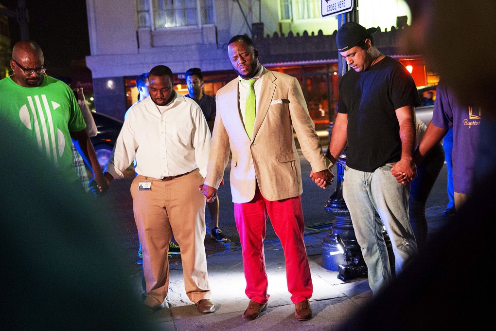 Worshippers gather to pray down the street from the Emanuel AME Church following a shooting. Authorities are viewing the incident as a hate crime. Photo: AP