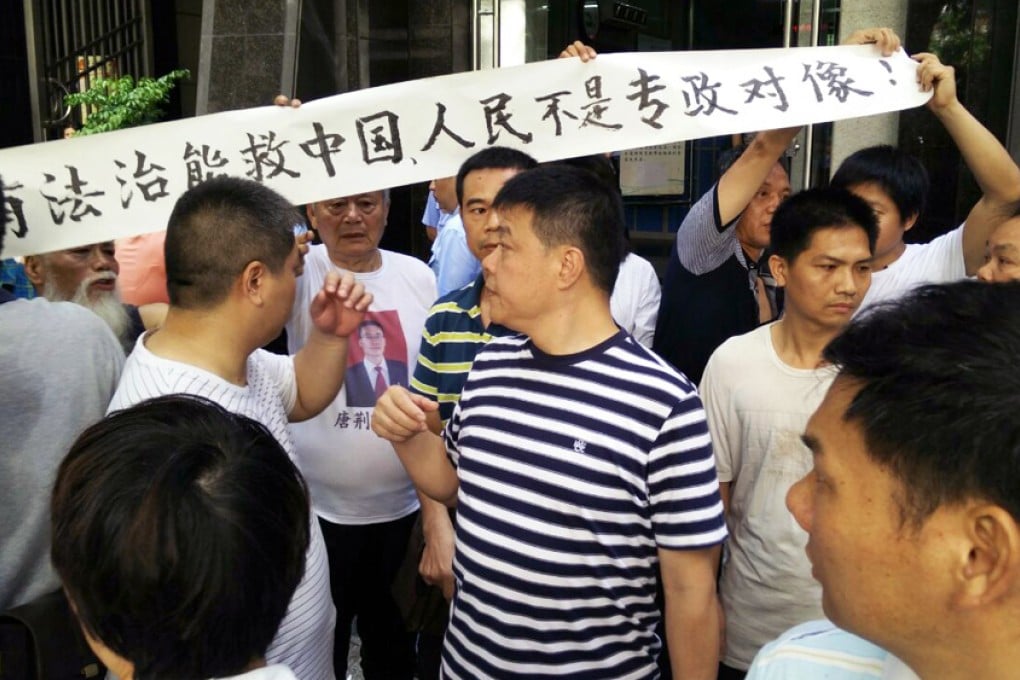 Tang Jingling's supporters, some in T-shirts bearing his photo, raise a banner outside court in Guangzhou yesterday. Photo: Mimi Lau