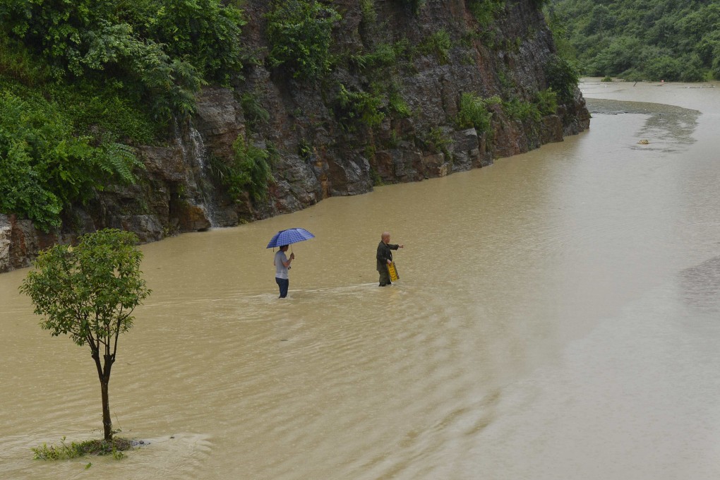 Two men walk across a flooded stretch of roadway in Kaili city in southwestern China's Guizhou province on Thursday after heavy rains. Photo: AP